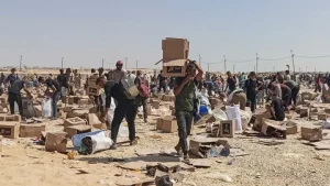 Children waiting for humanitarian aid in Gaza 2026 amid destroyed buildings as the Gaza humanitarian crisis deepens under aid access restrictions.